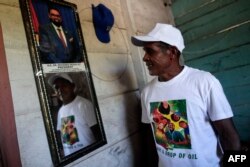 Un residente de la aldea de Arau posa junto a una fotografía del presidente de Guyana, Irfaan Ali. (Roberto Cisneros/AFP)
