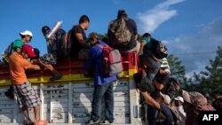 Migrantes hondureños que forman parte de la caravana que se dirige a EEUU se suben a un camión en Oaxaca, México.