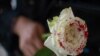 Una mujer sostiene una rosa "ensangrentada" en señal de luto por los feminicidios. (Pedro Pardo/AFP/Archivo)
